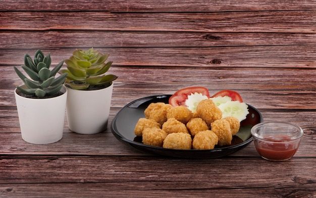 Nuggets de frango com salada e molho de tomate ao lado de cacto