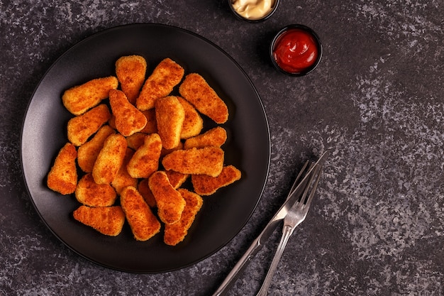 Nuggets de frango cozidos em um prato com molhos