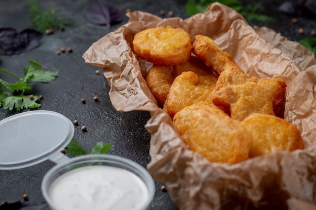 Nuggets de frango crocantes deliciosos em um fundo de pedra escura com molho cremoso. Restaurante fast food. Opção saudável de fast food.