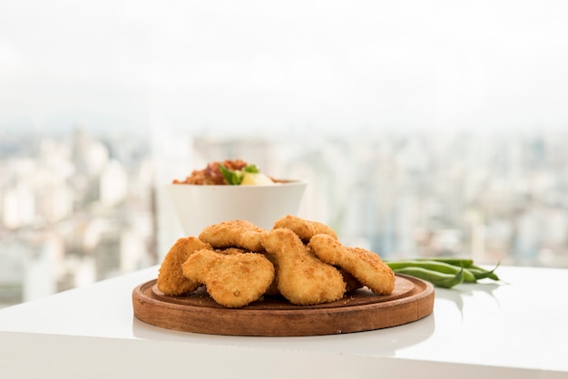 Foto nuggets de frango crocantes servidos na chapa de madeira