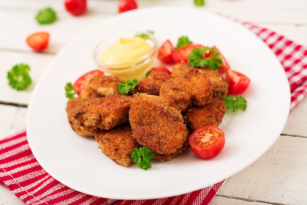 Nuggets de frango e molho no prato sobre um fundo branco de madeira