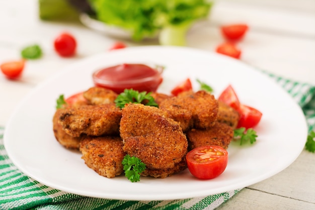 Nuggets de frango e molho no prato sobre um fundo branco de madeira