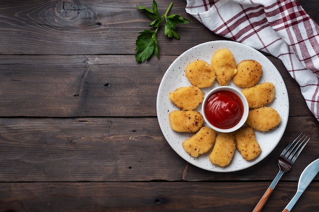 Nuggets de frango frito com molho de ketchup de tomate. mesa de madeira. Copie o espaço.