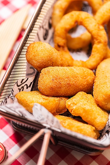 Nuggets de frango frito e anéis de cebola à milanesa em uma cesta em um café. Comida rápida