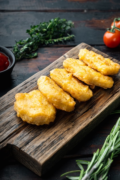 Nuggets de frango frito na mesa de madeira escura.