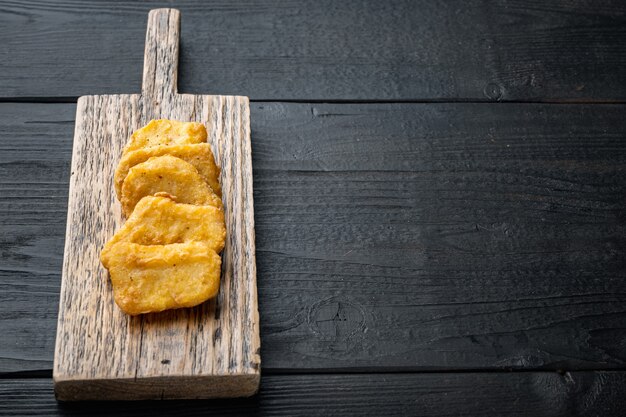 Nuggets de frango frito na mesa de madeira preta.