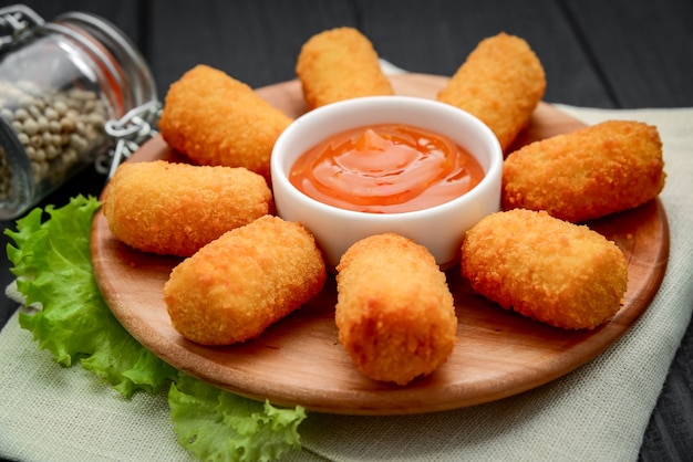 Nuggets de queijo com molho de manga em prato de madeira