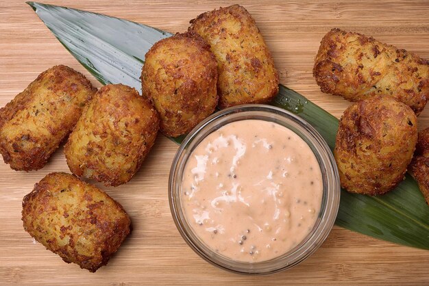 Nuggets fritos con salsa sobre una tabla de madera con una vista superior de hojas de bambú