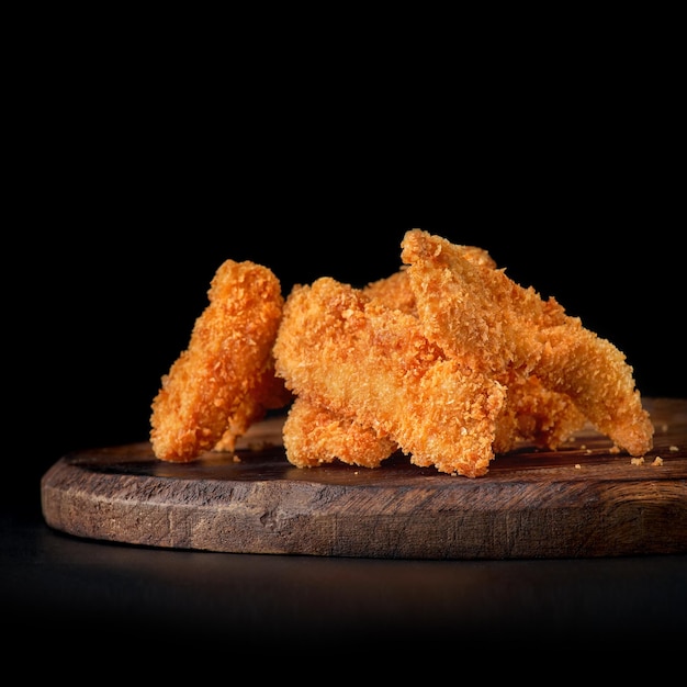 Nuggets de pollo en bandeja de madera aislado en negro Copiar menú espacial