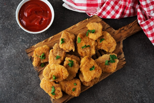 Nuggets de pollo caseros con hierbas y salsa de tomate sobre una tabla de madera