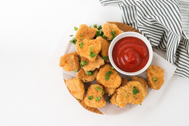 Nuggets de pollo caseros con salsa de tomate sobre una tabla de madera