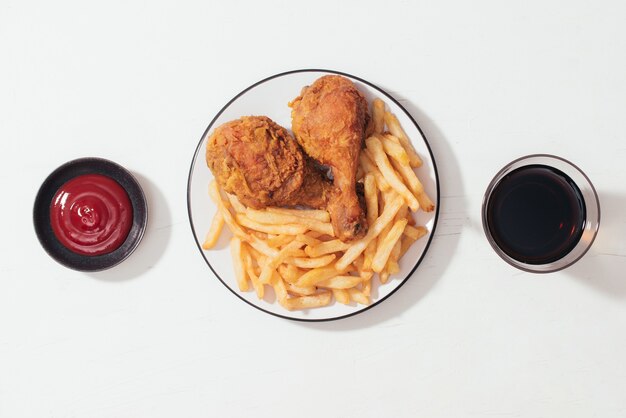 Nuggets de pollo crujiente empanizado frito con papas fritas en placa de madera, salsa de tomate y refresco en el lateral