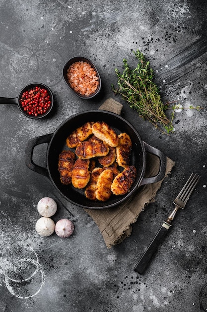 Nuggets de pollo dorados fritos en aceite caliente sobre fondo de mesa de piedra oscura negra vista superior plana con espacio de copia para texto