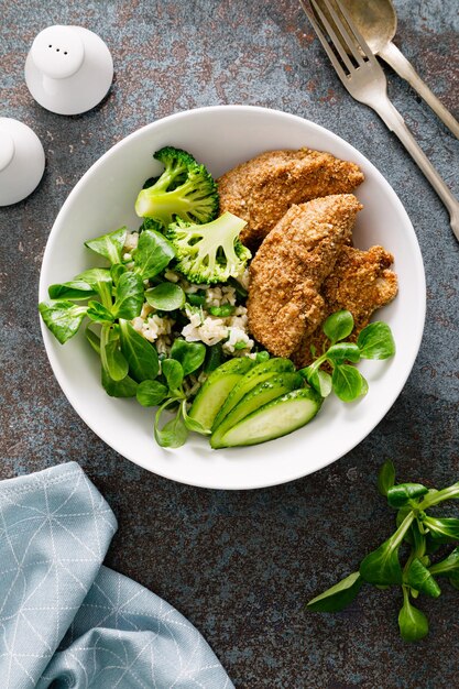 Nuggets de pollo con ensalada de maíz fresco brócoli pepino y arroz Vista superior