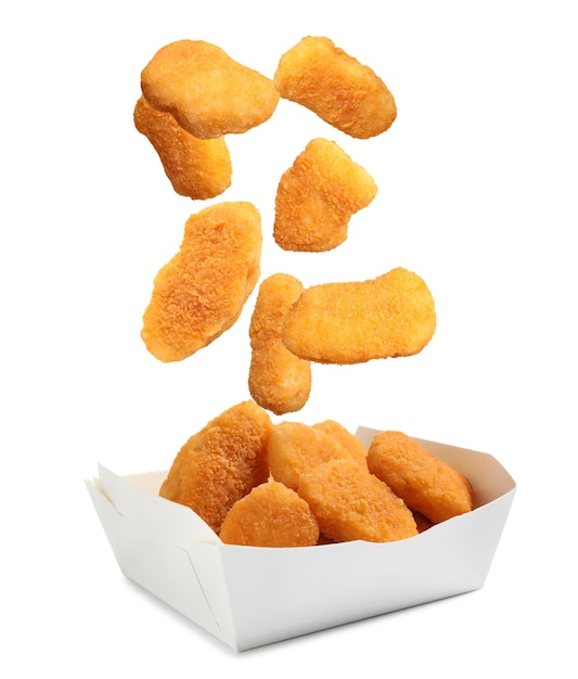 Nuggets de pollo frescos cayendo en un recipiente sobre un fondo blanco