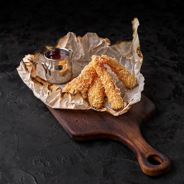 Nuggets de pollo frito crujiente con salsa de tomate. Aperitivo sabroso para cerveza sobre un fondo oscuro