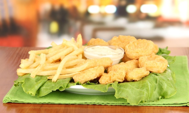 Nuggets de pollo frito con papas fritas y salsa en la mesa del café