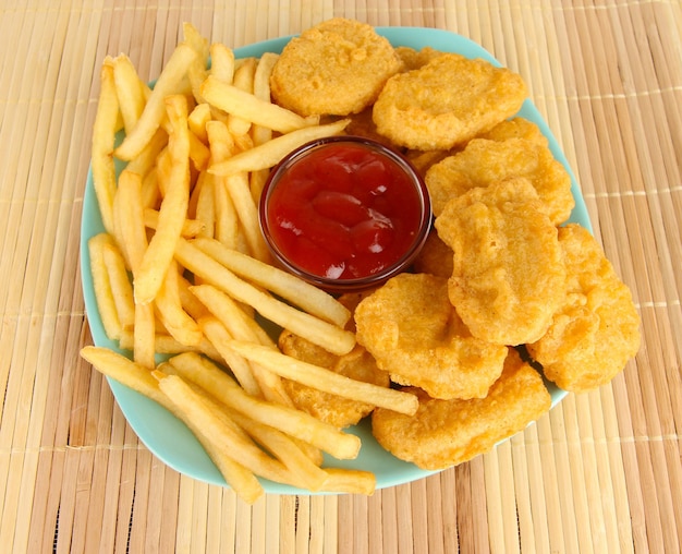 Nuggets de pollo frito con papas fritas y salsa en la mesa en el parque