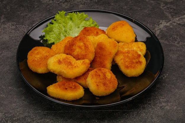 Nuggets de pollo frito servido con hojas de ensalada