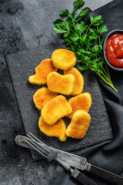 Nuggets de pollo horneados caseros crujientes. Fondo oscuro. Vista superior.