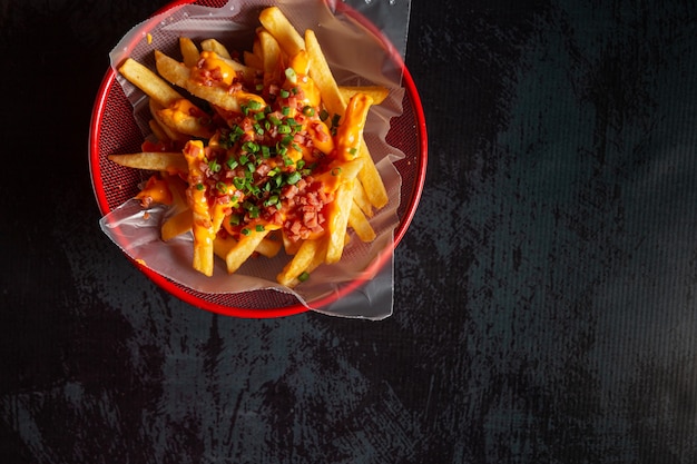 Nuggets de pollo en una olla roja con papas fritas y queso