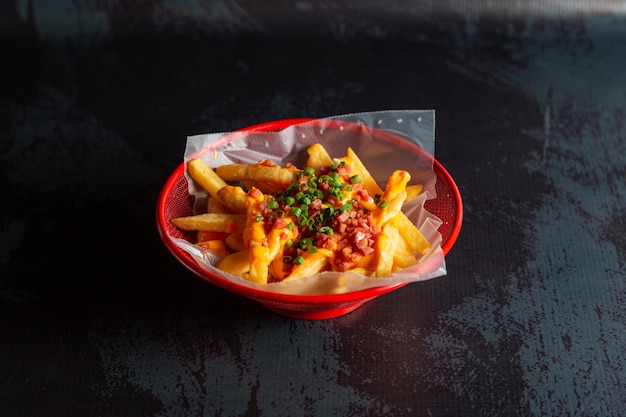 Nuggets de pollo en una olla roja con papas fritas y queso