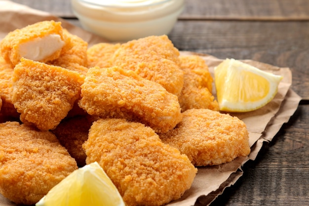 Nuggets de pollo con salsa blanca sobre un fondo de madera marrón. primer plano de comida rápida