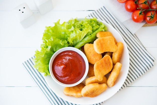 Nuggets de pollo con salsa y hierbas en un plato, vista superior