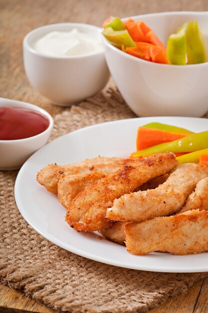 Nuggets de pollo con salsa y verduras.