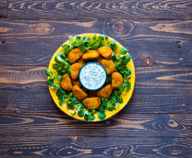 Foto nuggets de pollo con salsa de yogurt sobre un fondo de madera