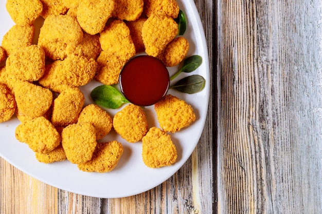 Nuggets de pollo con salsas sobre fondo de madera.