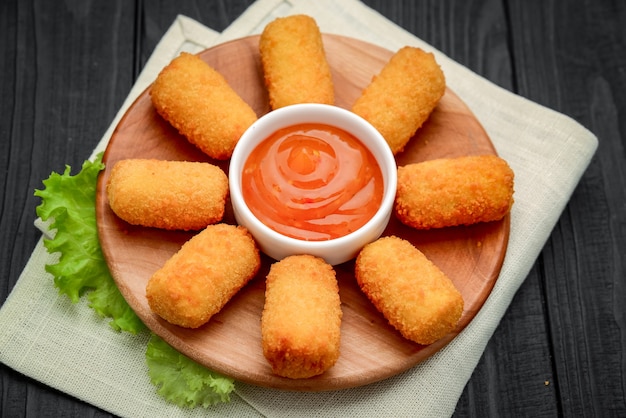 Nuggets de queso con salsa de mango en una placa de madera