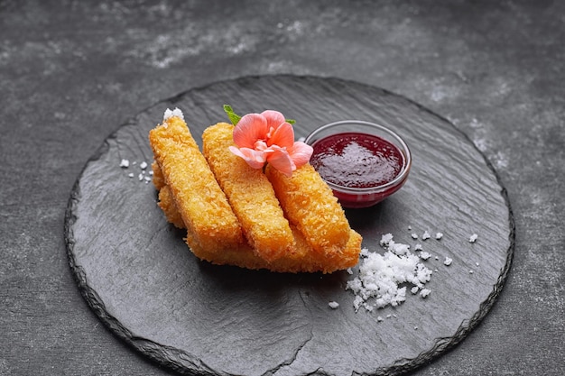 Nuggets de queso con salsa sobre un fondo oscuro