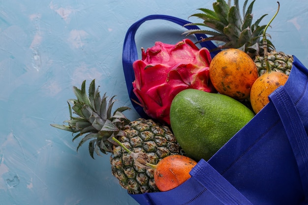 Null-Abfall-Konzept, blaue Einkaufstextil-Tasche mit frischen tropischen Früchten Mango, Ananas, Drache und Passionsfrucht