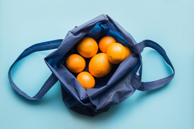 Null-Abfall-Konzept. Blaue Einkaufstextiltasche mit frischer Orange und Gemüse.