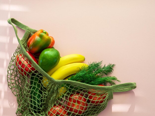 Foto null-abfall-lebensmittel-shopping öko-freundliche natürliche tasche mit obst und gemüse nachhaltiges lebensstilkonzept plastikfreie gegenstände wiederverwenden, recycling ablehnen, lebensmittel auf rosa hintergrund flach legen