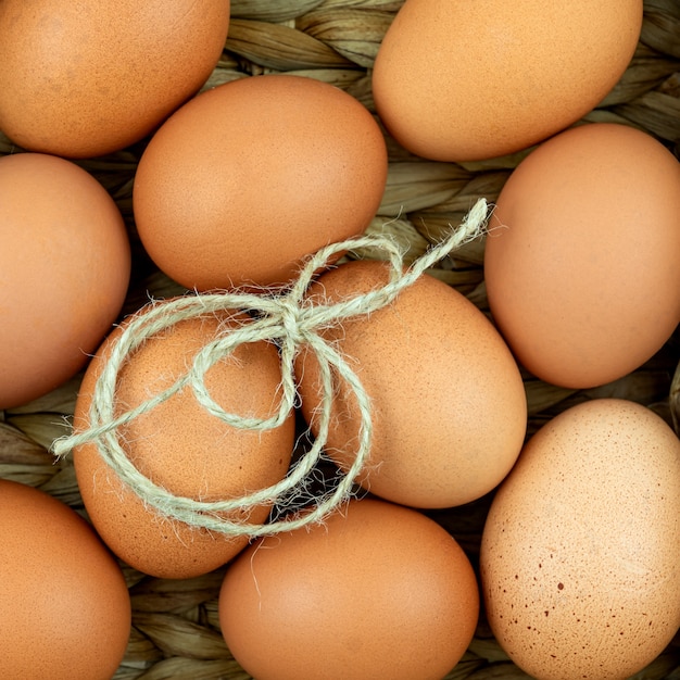 Null Abfall Ostern Hintergrund. Kein Plastikkonzept. Minimaler Stil. Beige Wasserhyazinthenbox mit braunen Hühnereiern auf Textilhintergrund.