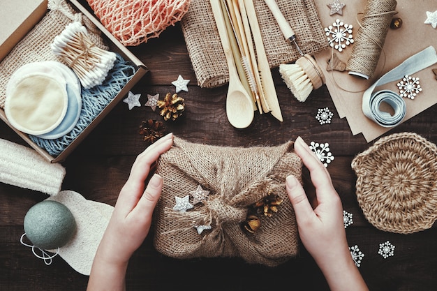 Null Abfall Weihnachten. Weibliche Hände halten Geschenk in Sackleinen gewickelt.