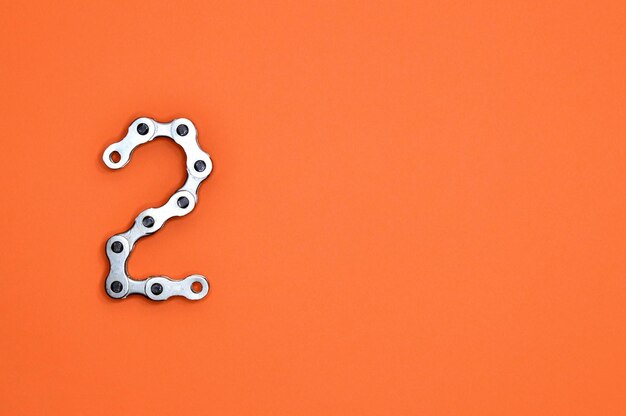 Number 2 Formed from Bicycle Chain on Orange Background