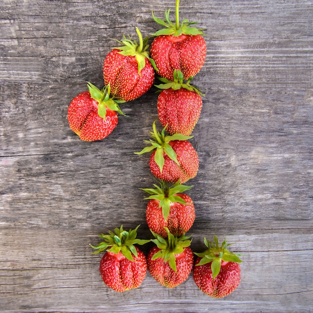 Número 1 de fresas sobre fondo de madera