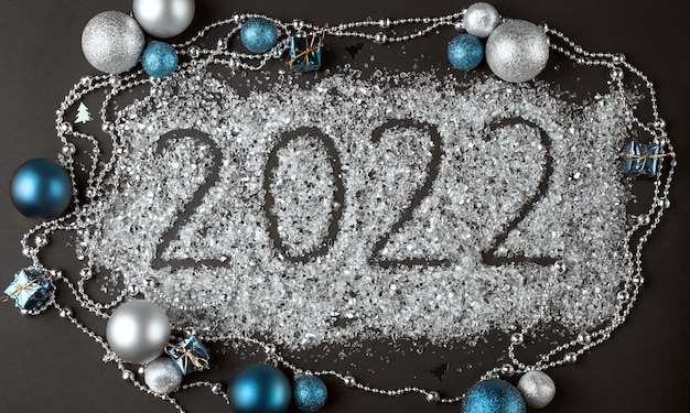 Número 2022 escrito en un brillo disperso y decoración navideña sobre un fondo oscuro