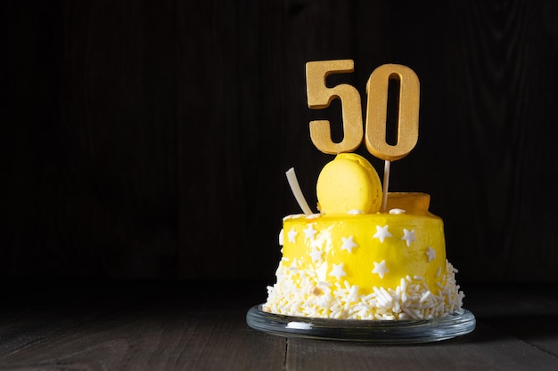 El número Cincuenta en un pastel amarillo para un aniversario o cumpleaños en una clave oscura