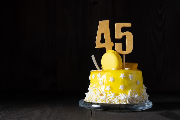 El número cuarenta y cinco en un pastel amarillo para un aniversario o cumpleaños en una clave oscura