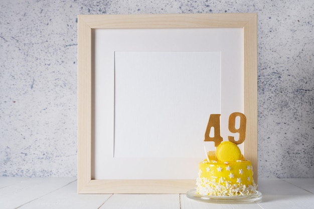 El número cuarenta y nueve en el pastel amarillo al lado de la maqueta de marco blanco con espacio de copia