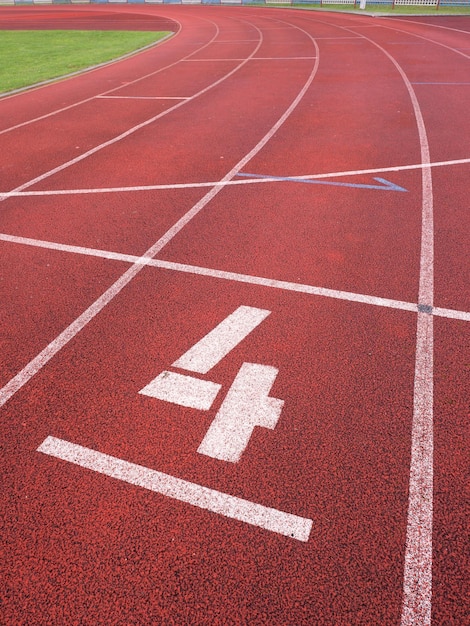 Número cuatro número de pista blanca en la textura de la pista de carreras de goma roja de las pistas de carreras en un estadio pequeño