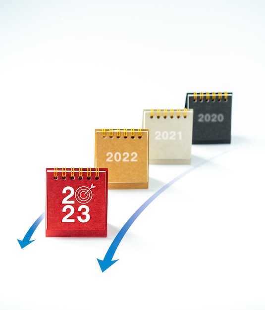 Número de ano novo de 2023 com ícone de alvo na capa do calendário de mesa na frente dos calendários dos anos anteriores com setas para a frente no fundo branco vertical Conceitos de liderança de objetivos de negócios