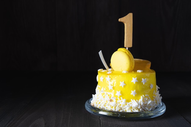 El número uno en un pastel amarillo para un aniversario o cumpleaños en una clave oscura