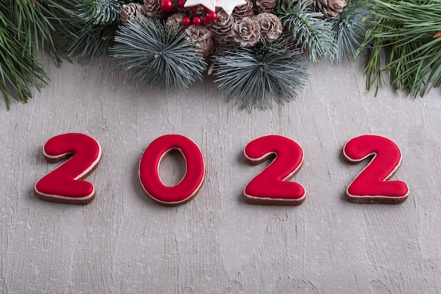 Número rojo 2022 de pan de jengibre y corona de navidad. Buen espíritu de año nuevo. Pared gris claro en el fondo.
