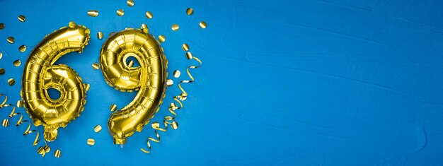 número sesenta y nueve globo de papel de aluminio amarillo dorado sobre fondo de hormigón azul tarjeta de cumpleaños o aniversario con la inscripción 69 celebración del aniversario