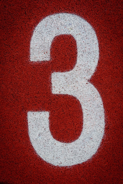 Foto el número tres al comienzo de una pista de atletismo en el estadio